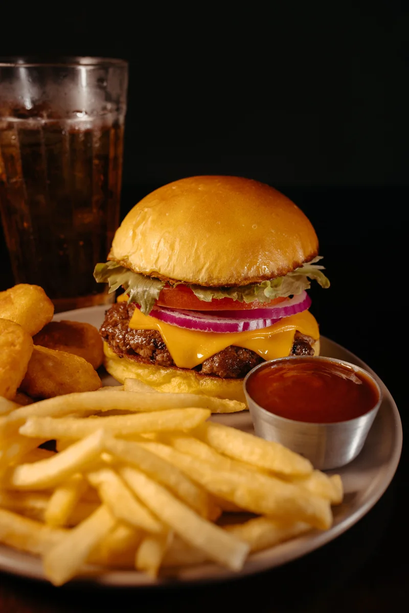 Burger avec frites et boisson sur fond sombre
